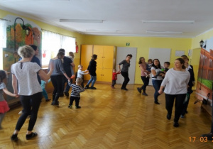 Dzieci i rodzice tańczą w parach z dziećmi w kole.